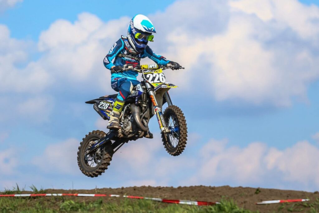 Motocross-Fahrer springt vor blauem Himmel ueber einen Huegel in Mecklenburg-Vorpommern