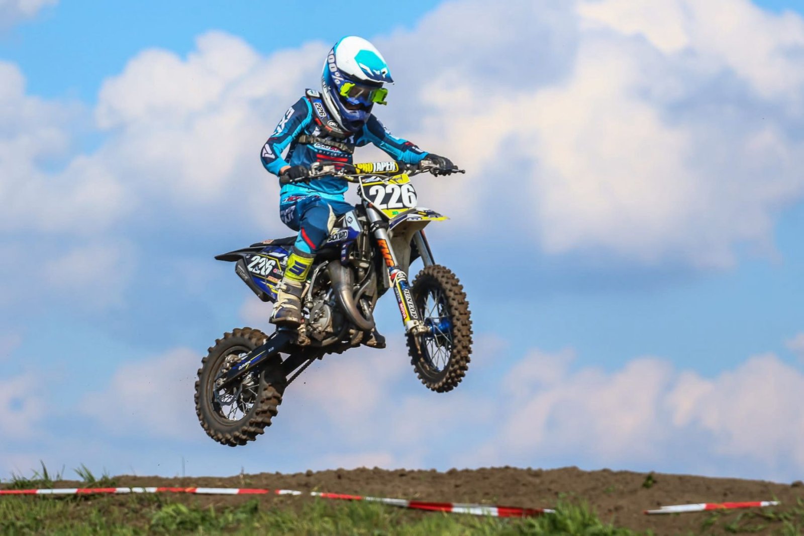 Motocross-Fahrer springt vor blauem Himmel ueber einen Huegel in Mecklenburg-Vorpommern